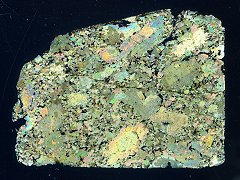 Thin Section image in partially cross-polarized light (pyroxene and olivine colors, maskelynite gray, glass veins and chromite black).