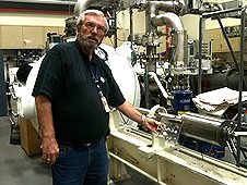 NASA - JSC Visit - Dr. Everett Gibson standing by the Light Gas Gun in a JSC laborator.