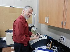 UCF Laboratory - Dr. Dan Britt holding Tissint stone next to the pycnometer that utilizes helium for density measurement. January 2012